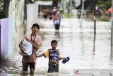 Warga melintasi jalan yang terendam banjir di desa Babadan, Kecamatan Sindang, Indramayu, Jawa Barat, Senin (8/2/2021). BPBD Kabupaten Indramayu mencatat sedikitnya 21 kecamatan di Indramayu terdampak banjir akibat luapan air dari sejumlah sungai yang berada di DAS Cimanuk-Cisanggarung dan DAS Citarum. ANTARA JABAR/Dedhez Anggara/agr