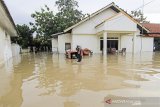 Warga melintasi jalan yang terendam banjir di desa Babadan, Kecamatan Sindang, Indramayu, Jawa Barat, Senin (8/2/2021). BPBD Kabupaten Indramayu mencatat sedikitnya 21 kecamatan di Indramayu terdampak banjir akibat luapan air dari sejumlah sungai yang berada di DAS Cimanuk-Cisanggarung dan DAS Citarum. ANTARA JABAR/Dedhez Anggara/agr