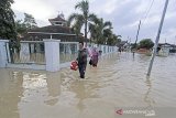 Warga melintasi jalan yang terendam banjir di desa Babadan, Kecamatan Sindang, Indramayu, Jawa Barat, Senin (8/2/2021). BPBD Kabupaten Indramayu mencatat sedikitnya 21 kecamatan di Indramayu terdampak banjir akibat luapan air dari sejumlah sungai yang berada di DAS Cimanuk-Cisanggarung dan DAS Citarum. ANTARA JABAR/Dedhez Anggara/agr