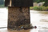 Warga melintas di dekat jembatan yang salah satu pilarnya ambles di Sungai Madiun, Kota Madiun, Jawa Timur, Jumat (5/2/2021). Menurut warga amblesnya pilar jembatan tersebut akibat derasnya arus sungai selama dua hari terakhir, dan warga sekitar menutup akses jembatan untuk semua jenis kendaraan guna menghindari terjadinya musibah. Antara Jatim/Siswowidodo/zk.