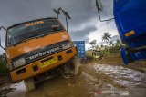 Sejumlah truk terperosok di Jalan Gubernur Sarkawi yang rusak di Kecamatan Sungai Tabuk, Kabupaten Banjar, Kalimantan Selatan, Senin (8/2/2021). Pasca banjir Ruas jalan nasional yang menghubungkan Provinsi Kalimantan Selatan dengan Provinsi Kalimantan Tengah tersebut rusak parah akibatnya aktivitas ekonomi terganggu karena menurut pengakuan sopir truk, mereka harus berjibaku bahkan sampai tiga hari lamanya untuk melintas di jalan yang merupakan akses utama angkutan barang. Foto Antaranews Kalsel/Bayu Pratama S.