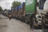 Pengendara melintas di samping truk yang antre di Jalan Gubernur Sarkawi akibat sejumlah truk terperosok di jalan yang rusak di Kecamatan Sungai Tabuk, Kabupaten Banjar, Kalimantan Selatan, Senin (8/2/2021). Pasca banjir Ruas jalan nasional yang menghubungkan Provinsi Kalimantan Selatan dengan Provinsi Kalimantan Tengah tersebut rusak parah akibatnya aktivitas ekonomi terganggu karena menurut pengakuan sopir truk mereka harus berjibaku bahkan sampai tiga hari lamanya untuk melintas di jalan yang merupakan akses utama angkutan barang. Foto Antaranews Kalsel/Bayu Pratama S.