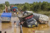 Sejumlah truk terperosok di Jalan Gubernur Sarkawi yang rusak di Kecamatan Sungai Tabuk, Kabupaten Banjar, Kalimantan Selatan, Senin (8/2/2021). Pasca banjir Ruas jalan nasional yang menghubungkan Provinsi Kalimantan Selatan dengan Provinsi Kalimantan Tengah tersebut rusak parah akibatnya aktivitas ekonomi terganggu karena menurut pengakuan sopir truk, mereka harus berjibaku bahkan sampai tiga hari lamanya untuk melintas di jalan yang merupakan akses utama angkutan barang. Foto Antaranews Kalsel/Bayu Pratama S.