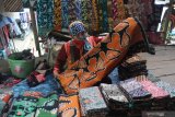 Pedagang menunggui batik dagangannya di Pasar Batik Tradisional, Pamekasan, Jawa Timur, Minggu (7/2/2021). Kebijakan Pemkab Pamekasan yang memberlakukan pakaian adat Madura, Baju Koko dan Batik Pamekasan, sebagai seragam Pegawai Negeri Sipil (PNS) dan non pegawai PNS disambut gembira oleh pelaku batik di daerah itu. Antara Jatim/Saiful Bahri/zk.