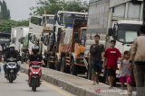 Pengendara sepeda motor melintas di samping truk pengangkut logistik yang berhenti beroperasi di ruas jalur pantura Pamanukan, Kabupaten Subang, Jawa Barat, Selasa (9/2/2021). Akses Jalan Pantura dari arah Jakarta menuju Cirebon maupun sebaliknya untuk sementara tidak dapat dilewati akibat banjir yang melanda kawasan Pamanukan sehingga membuat sejumlah truk pengangkut logistik berhenti di ruas jalan raya. ANTARA JABAR/Novrian Arbi/agr