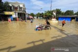 Sejumlah warga melintasi jalan yang terendam banjir di Indramayu, Jawa Barat, Selasa (9/2/2021). Pemerintah Kabupaten Indramayu menetapkan status tanggap darurat banjir hingga 17 februari mendatang, keputusan ini diambil akibat mengingat musibah banjir yang terjadi semakin meluas. ANTARA JABAR/Dedhez Anggara/agr