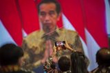 Seorang tamu undangan merekam Presiden Joko Widodo saat berpidato secara virtual dalam acara puncak Hari Pers Nasional (HPN) 2021 di Ancol, Jakarta, Selasa (9/2/2021). Presiden dalam pidatonya selain mengapresiasi peran insan pers yang membantu pemerintah mengedukasi penerapan protokol kesehatan juga mengatakan pemerintah membebaskan pajak penghasilan karyawan bagi wartawan untuk meringankan beban insan pers Indonesia di tengah menghadapi masa sulit akibat pandemi COVID-19. ANTARA FOTO/Aditya Pradana Putra/rwa.