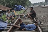 Sejumlah warga pengungsi banjir beristirahat di lintasan rel kereta yang tidak terpakai di Desa Waringinjaya, Cikarang, Kabupaten Bekasi, Jawa Barat, Selasa (9/2/2021). Menurut warga, para mereka sudah tiga hari berada di pengungisan akibat rumah yang masih tergenang banjir luapan sungai Citarum dan Cibe'et. ANTARA FOTO/Fakhri Hermansyah/hp.