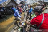 Tim Federasi Arung Jeram Indonesia (FAJI) Kalsel menurunkan bantuan cleaning kit dari atas perahu bermesin di Desa Keliling Benteng Ulu, Kabupaten Banjar, Kalimantan Selatan, Jumat (12/1/2021). Satgas banjir FAJI Kalsel menyalurkan bantuan 100 cleaning kit dari Global Rescue Network (GRN) kepada warga korban banjir di Kabupaten Banjar. Foto Antaranews Kalsel/Bayu Pratama S.