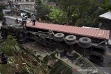 Petugas kepolisian memeriksa truk kontainer bermuatan tepung kelapa yang terguling di jalan raya Bandung-Tasikmalaya, Malangbong, Kabupaten Garut, Jawa Barat, Kamis (11/2/2021). Kecelakaan truk tersebut diduga karena rem blong dan tidak ada korban jiwa dalam peristiwa tersebut. ANTARA JABAR/Candra Yanuarsyah/agr