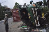 Warga melihat kondisi truk kontainer bermuatan tepung kelapa yang terguling di jalan raya Bandung-Tasikmalaya, Malangbong, Kabupaten Garut, Jawa Barat, Kamis (11/2/2021). Kecelakaan truk tersebut diduga karena rem blong dan tidak ada korban jiwa dalam peristiwa tersebut. ANTARA JABAR/Candra Yanuarsyah/agr