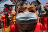 Warga berkostum Dewa Rejeki (kiri) bersama rombongan dengan mengenakan masker berkeliling di kampung pecinan di Kapasan Dalam, Surabaya, Jawa Timur, Jumat (12/2/2021). Kegiatan itu untuk merayakan Tahun Baru Imlek 2572. Antara Jatim/Didik/Zk