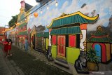 Warga berfoto dengan latar belakang mural di kampung Pecinan di Kapasan Dalam, Surabaya, Jawa Timur, Kamis (11/2/2021). Mural itu guna memperindah salah satu kampung Pecinan tertua di Surabaya tersebut. Antara Jatim/Didik/Zk