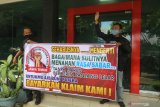 Dua orang nasabah membentangkan poster bertulis tuntutan pencairan klaim asuransi di depan kator AJB Bumiputera 1912 di Kota Kediri, Jawa Timur, Kamis (11/2/2021). Puluhan nasabah perwakilan dari Blitar, Tulungagung, Trenggalek, Ponorogo, Madiun, dan Kediri mendatangi kantor Bumiputera guna menuntut klaim asuransi yang tak kunjung cair. Antara Jatim/Prasetia Fauzani/zk.