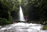 Wisatawan bermain di bawah air terjun telunjuk raung di Songgon, Banyuwangi, Jawa Timur, Minggu (14/2/2021). Wisata air terjun yang terletak di kaki gunung raung itu menjadi salah satu destinasi wisata alam yang menawarkan keindahan alam yang masih asri. Antara Jatim/Budi Candra Setya/zk.