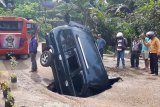 Sebuah minibus terperosok ke gorong-gorong yang tiba-tiba ambles