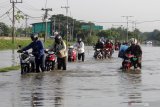 Pengendara menerobos banjir yang menggenangi jalan raya Porong, Sidoarjo, Jawa Timur, Selasa (16/2/2021). Curah hujan yang tinggi sejak Senin (15/2) malam mengakibatkan banjir yang merendam jalan raya Porong sehingga mengganggu kelancaran transportasi umum. Antara Jatim/Umarul Faruq/zk