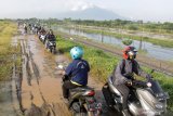 Sejumlah pengendara sepeda motor melewati tanggul penahan lumpur Lapindo untuk menghindari banjir di jalan raya Porong, Sidoarjo, Jawa Timur, Selasa (16/2/2021). Curah hujan yang tinggi sejak Senin (15/2) malam mengakibatkan banjir yang merendam jalan raya Porong sehingga mengganggu kelancaran transportasi umum. Antara Jatim/Umarul Faruq/zk