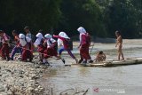 MURID SEBERANGI SUNGAI DENGAN RAKIT BAMBU DI PEDALAMAN ACEH. Sejumlah murid sekolah dasar menggunakan rakit dari bambu menyeberangi sungai saat pulang sekolah di Desa Siron Krueng, Kecamatan Kuta Cot Glee, Kabupaten Aceh Besar, Aceh, Rabu (17/2/2021). Pascaputusnya jembatan gantung diterjang banjir sekitar lima tahun lalu, murid sekolah dasar terpaksa menyeberangi sungai menggunakan rakit dengan mendapat pengawalan ketat orang tua mereka dan selain kekhawatiran keselamatan anak mereka pascapenangkapan dua ekor buaya oleh petugas Balai Konservasi Sumber Daya Alam (BKSDA) pertengah tahun 2020 di sungai tersebut. ANTARA FOTO/Ampelsa.