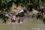 MURID SEBERANGI SUNGAI DENGAN RAKIT BAMBU DI PEDALAMAN ACEH. Sejumlah murid sekolah dasar menggunakan rakit dari bambu menyeberangi sungai saat pulang sekolah di Desa Siron Krueng, Kecamatan Kuta Cot Glee, Kabupaten Aceh Besar, Aceh, Rabu (17/2/2021). Pascaputusnya jembatan gantung diterjang banjir sekitar lima tahun lalu, murid sekolah dasar terpaksa menyeberangi sungai menggunakan rakit dengan mendapat pengawalan ketat orang tua mereka dan selain kekhawatiran keselamatan anak mereka pascapenangkapan dua ekor buaya oleh petugas Balai Konservasi Sumber Daya Alam (BKSDA) pertengah tahun 2020 di sungai tersebut. ANTARA FOTO/Ampelsa.