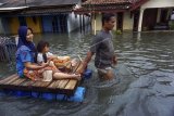 Warga menaiki perahu buatan saat banjir di Pekalongan, Jawa Tengah, Rabu (17/2/2021). Sebanyak 1.643 warga mengungsi di beberapa titik di Kota Pekalongan. ANTARA FOTO/Harviyan Perdana Putra/nym.