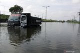 Truk terjebak banjir di jalan raya Porong, Sidoarjo, Jawa Timur, Rabu (17/2/2021). Curah hujan yang tinggi selama beberapa hari terakhir mengakibatkan banjir yang merendam jalan raya Porong sehingga mengganggu kelancaran transportasi umum. Antara Jatim/Umarul Faruq/zk