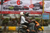 Pengendara motor melintas di depan spanduk yang memuat materi promosi pembelian mobil dengan relaksasi Pajak Penjualan Atas Barang Mewah (PPnBM) di depan diler Toyota Auto2000, Malang, Jawa Timur, Senin (1/3/2021). Pemerintah melalui Kementerian Koordinator Bidang Perekonomian memberlakukan kebijakan relaksasi Pajak Penjualan Atas Barang Mewah (PPnBM) dengan syarat tertentu yang diterapkan secara bertahap yakni mulai pada bulan Maret hingga Desember 2021. Antara Jatim/Ari Bowo Sucipto/zk.