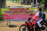 Pengendara sepeda motor melintasi poster pemblokiran di jalan masuk pemukiman dalam kawasan sumur minyak Kenali Asam (KAS) Pertamina EP Asset 1 Jambi Field, Kota Baru, Jambi, Kamis (4/3/2021). Warga di kawasan tersebut menutup akses masuk kendaraan pengangkut minyak Pertamina karena dinilai merusak jalan. ANTARA FOTO/Wahdi Septiawan/rwa.