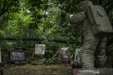 Pengunjung melihat karya lukisan pada Pameran Trees Of Life di Hutan Babakan Siliwangi Bandung, Jawa Barat, Sabtu (6/3/2021). Pameran Lukisan karya perupa Hassan Pratama tersebut mengedepankan seni lukis teks visual abstraksi, makna simbolik dan ikonografi dalam pelbagai tafsir atas lingkungan hidup serta refleksi kehidupan pada situasi saat ini di tengah pandemi. ANTARA JABAR/Novrian Arbi/agr