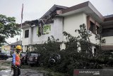 Petugas melintas di depan pohon tumbang yang menimpa kendaraan di Kantor ATR/BPN Kanwil Jawa Barat di Jalan Soekarno-Hatta, Bandung, Jawa Barat, Senin (8/3/2021). Pohon tumbang yang menimpa sejumlah kendaraan dan menghancurkan bagian depan atap gedung tersebut diakibatkan oleh angin kencang dan hujan deras yang melanda Bandung Raya pada Senin (8/3) siang hingga sore hari. ANTARA JABAR/Raisan Al Farisi/agr