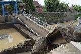 Warga melihat kondisi jembatan yang putus dan ambrol di kasawan Dam Piring Kota Madiun, Jawa Timur, Rabu (10/3/2021). Menurut warga jembatan serta bangunan dam tersebut putus dan ambrol pada Rabu (10/3) dini hari akibat banjir yang terjadi beberapa kali sebelumnya. Antara Jatim/Siswowidodo/zk