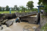 Warga melihat kondisi jembatan yang putus dan ambrol di kasawan Dam Piring Kota Madiun, Jawa Timur, Rabu (10/3/2021). Menurut warga jembatan serta bangunan dam tersebut putus dan ambrol pada Rabu (10/3) dini hari akibat banjir yang terjadi beberapa kali sebelumnya. Antara Jatim/Siswowidodo/zk