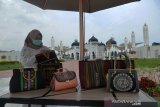 Keberadaan Galeri Suvenir di Masjid Raya Baiturrahman. Pelaku usaha menata aneka produk kerajinan khas Aceh di depan ruangan galeri dan suvenir menara Masjid Raya Baiturrahman, Banda Aceh, Aceh, Sabtu (20/3/2021). Keberadaan galeri dan suvenir UMKM binaan BUMN di situs sejarah Masjid Raya Baiturrahman itu untuk memanfaatkan peluang pasar dari kunjungan wisatawan ke rumah ibadah tersebut dalam upaya promosi dan sekaligus peningkatan omzet penjualan aneka produk kerajinan khas Aceh. ANTARA FOTO/Ampelsa