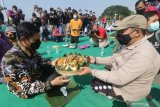 Wali Kota Kediri Abdullah Abu Bakar (kiri) secara simbolis memberikan nasi tumpeng kepada pegiat dan pemerhati budaya Imam Mubarok (kanan) di atas Jembatan Lama Kediri (Brug Over Den Brantas de Kediri) di Kota Kediri, Jawa Timur, Kamis (18/3/2021). Kegiatan berjemur sekaligus makan bareng nasi tumpeng dan 152 bungkus nasi takir tersebut guna memperingati 152 tahun berdirinya Jembatan Lama Kediri yang merupakan jembatan cagar budaya berkonstruksi besi pertama di pulau Jawa. Antara Jatim/Prasetia Fauzani/zk