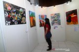 Pengunjung melihat lukisan yang ditampilkan dalam Pameran Re Kreasi Warna Khatulistiwa di Museum Negeri Pontianak, Kalimantan Barat, Sabtu (20/3/2021). Pameran yang melibatkan 30 seniman Kalbar tersebut menampilkan 52 lukisan dan satu karya pahat  tersebut bercerita tentang sosial budaya, lingkungan, hingga pandemi COVID-19 di bumi khatulistiwa. ANTARA FOTO/Jessica Helena Wuysang