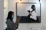 Pengunjung melihat lukisan yang ditampilkan dalam Pameran Re Kreasi Warna Khatulistiwa di Museum Negeri Pontianak, Kalimantan Barat, Sabtu (20/3/2021). Pameran yang melibatkan 30 seniman Kalbar tersebut menampilkan 52 lukisan dan satu karya pahat  tersebut bercerita tentang sosial budaya, lingkungan, hingga pandemi COVID-19 di bumi khatulistiwa. ANTARA FOTO/Jessica Helena Wuysang