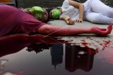 Dua aktivis Jeda untuk Iklim melakukan aksi teatrikal menggunakan cairan berwarna merah di kawasan Dukuh Atas, Jakarta, Jumat (19/3/2021). Dalam aksinya mereka meminta pemerintah mendeklarasikan darurat iklim untuk menyelamatkan masyarakat dari bencana krisis iklim. ANTARA FOTO/Wahyu Putro A/wsj.f