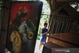 Seorang anak bermain angklung di samping karya seni lukisan yang dipamerkan di Saung Angklung Udjo, Bandung, Jawa Barat, Selasa (23/3/2021). Saung Angklung Udjo (SAU)menggelar pameran seni lukis dan fotografi dengan tema 