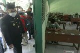 Bupati Kediri Hanindhito Himawan Pramana (kiri) memantau pelaksanaan Ujian Satuan Pendidikan (USP) daring di SMP Negeri 1 Ngasem, Kediri, Jawa Timur, Kamis (25/3/2021). Sejumlah sekolah di daerah tersebut mewajibkan siswa hadir di sekolah dengan menerapkan protokol kesehatan COVID-19 meskipun USP diselenggarakan secara daring guna mempermudah pemantauan. Antara Jatim/Prasetia Fauzani/zk