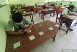 Pelajar mengerjakan soal Ujian Satuan Pendidikan (USP) mata pelajaran Pendidikan Pancasila dan Kewarganegaraan menggunakan gawai di SMP Negeri 1 Ngasem, Kediri, Jawa Timur, Kamis (25/3/2021). Sejumlah sekolah di daerah tersebut mewajibkan siswa hadir di sekolah dengan menerapkan protokol kesehatan COVID-19 meskipun USP diselenggarakan secara daring guna mempermudah pemantauan. Antara Jatim/Prasetia Fauzani/zk