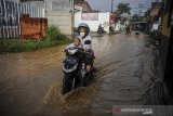 Pengendara melintasi banjir di Cingised, Bandung, Jawa Barat, Minggu (28/3/2021). Hujan dengan intensitas tinggi pada Sabtu (27/3) membuat kawasan tersebut terendam banjir luapan Sungai Cironggeng setinggi 30 hingga 60 sentimeter. ANTARA JABAR/Raisan Al Farisi/agr