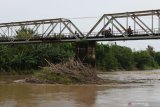 Pengendara melintas di atas jembatan Sungai Madiun yang pada pilarnya tersangkut tumpukan sampah di perbatasan wilayah Kota dan Kabupaten Madiun Jawa Timur, Selasa (30/3/2021). Menurut warga tumpukan sampah yang sebagian besar terdiri pohon bambu tersebut terbawa air saat banjir, dan bila tumpukan sampah terus semakin bertambah bisa mengakibatkan kerusakan jembatan saat banjir dengan arus deras. Antara Jatim/Siswowidodo/zk.