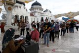 Warga antre untuk mendapatkan suntikan vaksin COVID-19 di halaman Masjid Raya Baiturrahman, Banda Aceh, Aceh, Selasa (30/3/2021). Dinas Kesehatan Provinsi Aceh menargetkan tiga ribu warga termasuk anggota TNI/Polri, wartawan, atlet PON dan petugas pelayanan publik akan mendapatkan vaksin di halaman masjid tersebut. Antara Aceh/Irwansyah Putra