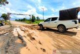 Pengendara mobil melintas di ruas jalan Margasari-Marabahan yang rusak di Kabupaten Tapin, Kalimantan Selata, Rabu (31/3/2021). Dinas Pekerjaan Umum dan Penataan Ruang (PUPR) Tapin menyatakan bahwa proses lelang telah selesai, selanjutnya perbaikan ruas jalan Margasari-Marabahan sepanjang 5 km antara Desa Margasari Hilir dan Desa Sungai Puting Kecamatan Candi Laras Utara (CLU) sisa jalan yang belum di aspal direncanakan dikerjakan pada April 2021. Foto Antaranews Kalsel/Bayu Pratama S.