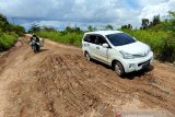 Pengendara sepeda motor melintas di ruas jalan Margasari-Marabahan yang rusak di Kabupaten Tapin, Kalimantan Selata, Rabu (31/3/2021). Dinas Pekerjaan Umum dan Penataan Ruang (PUPR) Tapin menyatakan bahwa proses lelang telah selesai, selanjutnya perbaikan ruas jalan Margasari-Marabahan sepanjang 5 km antara Desa Margasari Hilir dan Desa Sungai Puting Kecamatan Candi Laras Utara (CLU) sisa jalan yang belum di aspal direncanakan dikerjakan pada April 2021. Foto Antaranews Kalsel/Bayu Pratama S.