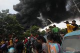 Warga menyaksikan terjadinya kebakaran sebuah pabrik dan gudang palet plastik di kawasan Tandes, Surabaya, Jawa Timur, Rabu (31/3/2021). Puluhan kendaraan pemadam kebakaran dikerahkan untuk memadamkan kebakaran itu. Antara Jatim/Didik/Zk