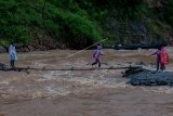 Warga melintasi sungai Ciberang menggunakan jembatan swadaya masyarakat di Desa Ciladaheun, Lebak, Banten, Selasa (30/3/2021). Menurut keterangan warga setempat, setahun pasca diterjang bencana banjir bandang jembatan yang merupakan akses jalan nasional tersebut belum dibangun dan tidak bisa dilalui kendaraan ketika hujan deras karena air sungai Ciberang meluap. ANTARA FOTO/Muhammad Bagus Khoirunas/aww.