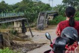 Warga melihat jembatan yang putus di Sungai Madiun, Kota Madiun, Jawa Timur, Jumat (2/4/2021). Jembatan tersebut putus karena salah satu pilarnya ambruk akibat banjir yang terjadi Kamis (1/4) malam. Antara Jatim/Siswowidodo/zk.