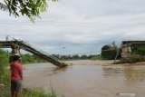 Warga melihat jembatan yang putus di Sungai Madiun, Kota Madiun, Jawa Timur, Jumat (2/4/2021). Jembatan tersebut putus karena salah satu pilarnya ambruk akibat banjir yang terjadi Kamis (1/4) malam. Antara Jatim/Siswowidodo/zk.