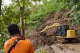 Pekerja menggunakan alat berat membersihkan reruntuhan tanah longsor dari tebing yang menimbun jalan di Desa Ngranget, Dagangan, Kabupaten Madiun, Jawa Timur, Jumat (2/4/2021). Tebing di lembah Gunung Wilis tersebut longsor akibat hujan deras Kamis (1/4) malam. Antara Jatim/Siswowidodo/zk.